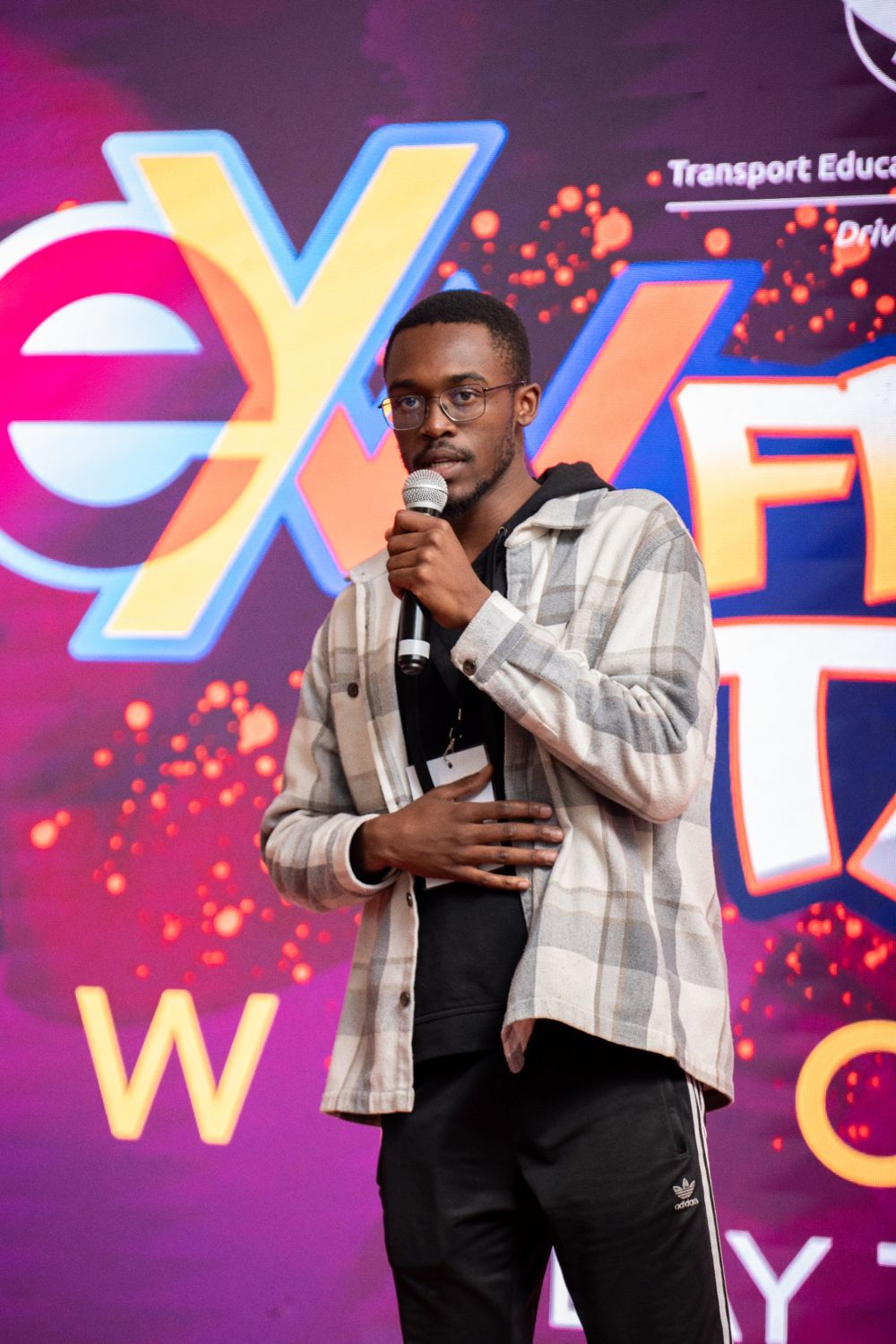 Wandile Hlatshwayo speaking into a microphone on stage at Empowa Youth Week