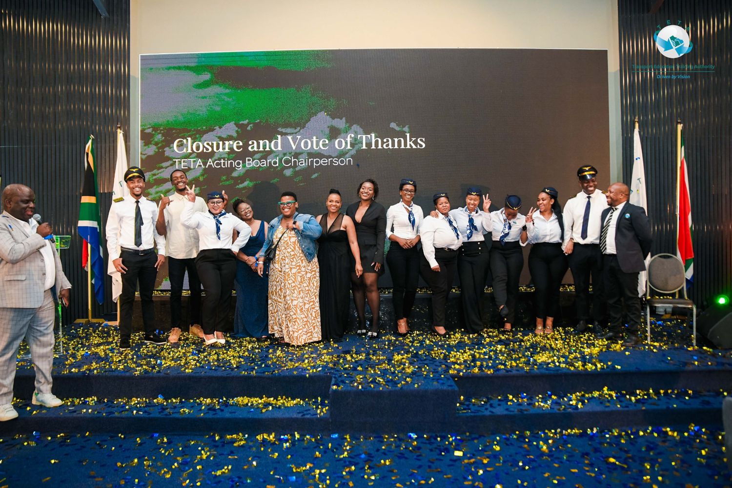 Team in pilot and cabin-crew outfits on a confetti-covered stage under the Closure and Vote of Thanks slide